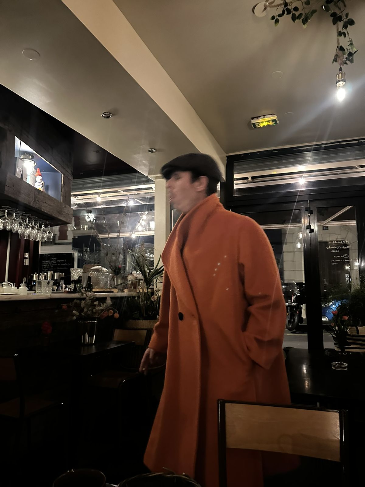 Ben en long manteau orange dans un café