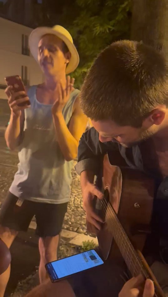 Ben chante dans la rue, la nuit, à côté d’un guitariste